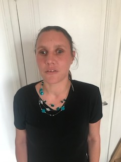 Portrait d’Alicia Riviere Anbarasan : femme aux cheveux attachés, portant un t-shirt noir et un collier de perles turquoise